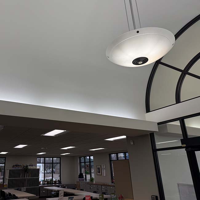 Large round ceiling light installed by a licensed & insured electrician above modern office desks.
