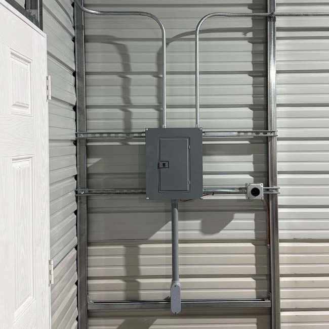 Gray electrical panel with metal conduit on white wall, installed by a Wisconsin Rapids electrician.