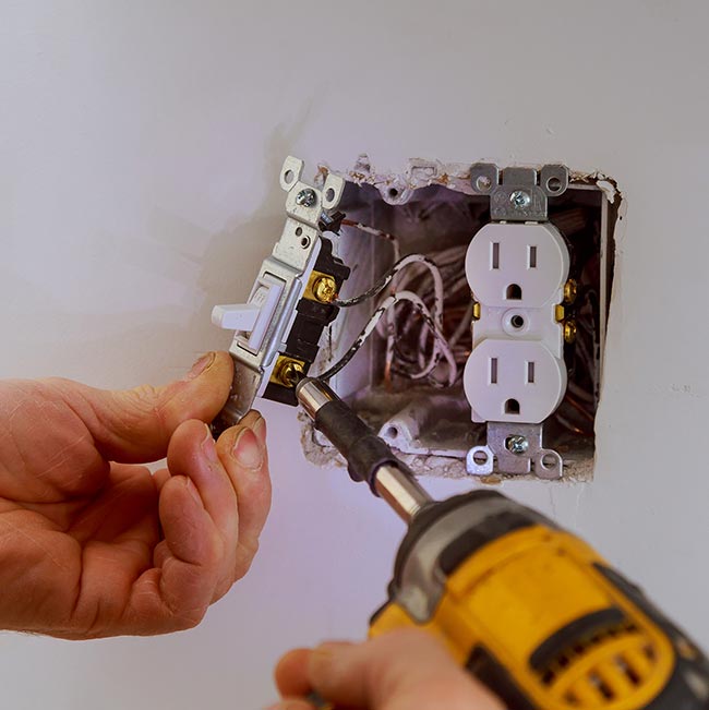 Hands installing an electrical light switch near an outlet in Wisconsin Rapids. Licensed & insured.